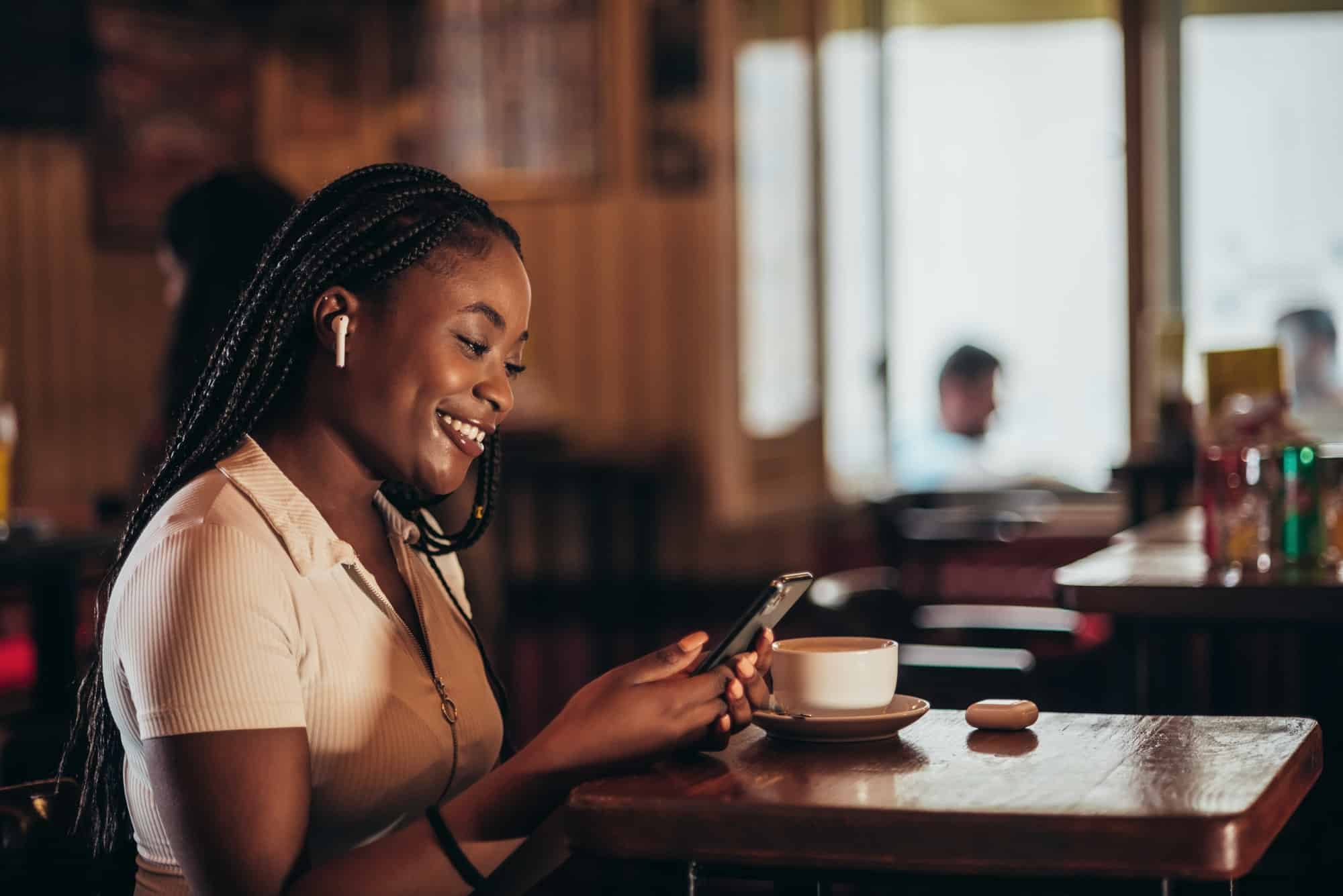 African american woman using smartphone while in a cafe